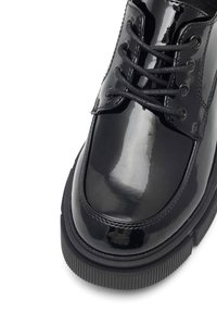 Czarne lakierowane buty skórzane z zaokrąglonym noskiem, z czarnymi sznurowadłami i teksturowaną gumową podeszwą. Gładka, błyszcząca powierzchnia z minimalnym wykończeniem.