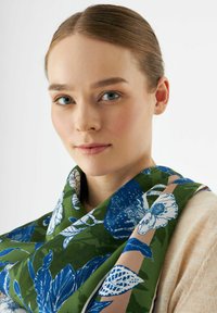 Bloemen sjaal met een groene basis en blauwe en witte botanische prints; soepele textuur; brede ontwerp gedrapeerd om de nek.