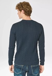 Maglione in blu navy a treccia, realizzato in un tessuto morbido, con polsini e orlo a coste, caratterizzato da un motivo testurizzato sul retro.