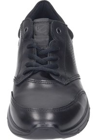 Black athletic shoe featuring smooth leather vamp, mesh tongue, round laces, and textured rubber sole with subtle perforations.