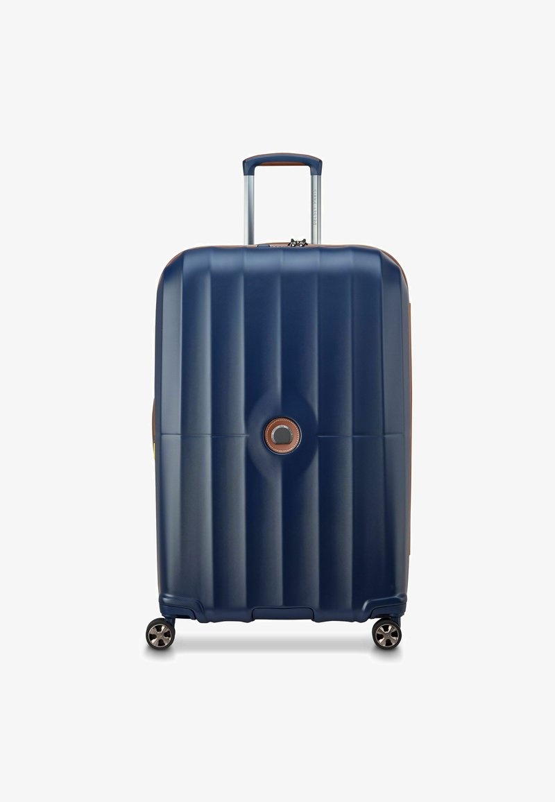 Navy hardshell koffer met gestreepte textuur, zilveren telescopische handvat, bruine accenten en vier zwarte wielen voor mobiliteit.