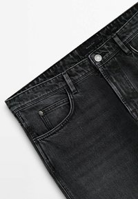 Jean en denim noir avec poches avant, passants pour ceinture et bouton argenté, étalé à plat sur un fond blanc.