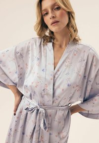 Jasnoniebieski kimono w kwiaty z szerokimi rękawami i paskiem do zawiązywania. Ozdobione rozproszonymi różowymi i fioletowymi wzorami kwiatowymi na jedwabistej fakturze.