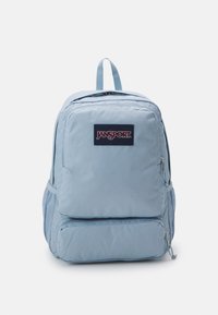 Mochila Jansport de color azul claro con dos compartimentos con cremallera, bolsillos laterales de malla y un asa de transporte en la parte superior. Textura de tela suave.