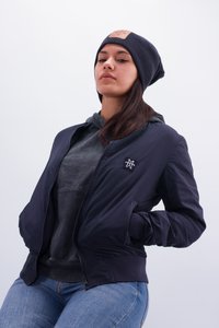 Marineblauer Bomberjacke mit geripptem Kragen, Reißverschluss vorne und Seitentaschen. Darunter ist ein grüner Hoodie sichtbar, kombiniert mit blauen Jeans.