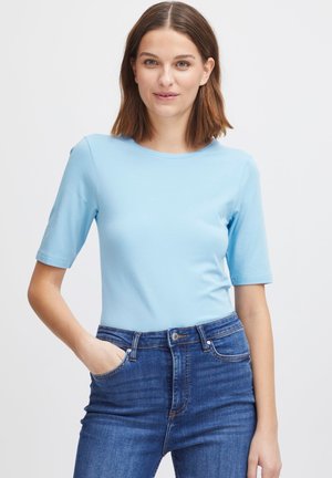 Light blue fitted t-shirt with short sleeves, round neckline, smooth texture, paired with high-waisted dark denim jeans.