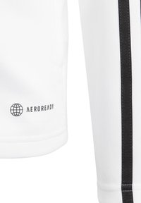 White athletic shirt featuring a textured fabric, black side stripes, and an "AEROREADY" logo near the hem. Minimalistic design.