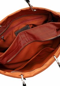 Innenansicht einer orangen Stoffhandtasche mit mehreren Fächern, darunter Reißverschlusssektionen und ein glattes, strukturiertes Futter. Akzente aus silberner Hardware.