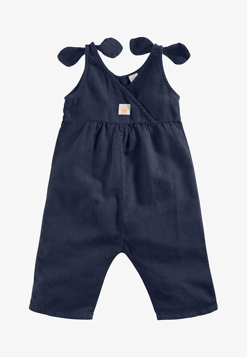Salopette in lino blu navy con spalline larghe legate a fiocco, scollatura avvolgente, vita arricciata e una piccola etichetta brandizzata vicino al petto.