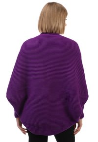 Poncho de punto morado con textura acanalada, mangas anchas y un corte holgado, que termina a la altura de las caderas. Sin cierres ni detalles adicionales visibles.