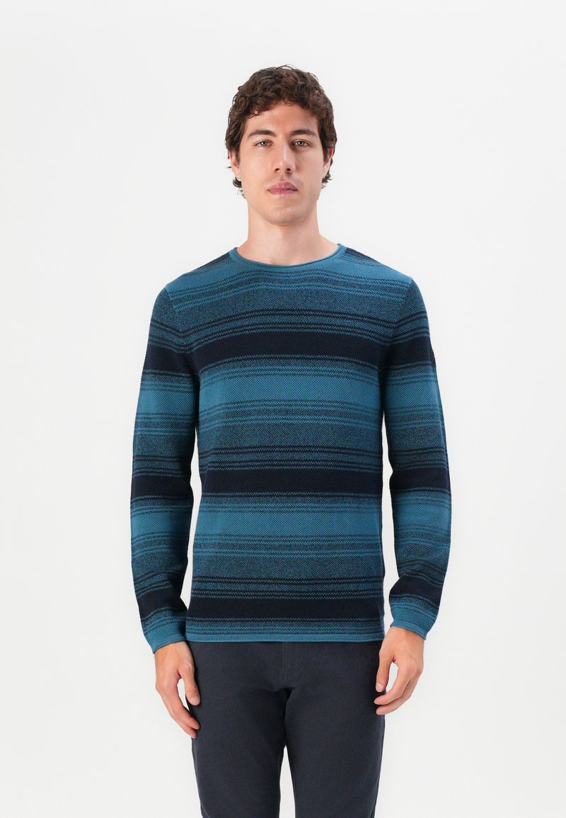 Blau- und schwarz gestreifter, langärmeliger Pullover mit Rundhalsausschnitt und strukturiertem Stoff, getragen von einem Model vor einem schlichten weißen Hintergrund.