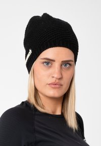 Black knit beanie with a ribbed lower edge, featuring a side logo accent. The texture is chunky, and it has a slouchy silhouette.