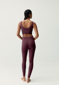 Reggiseno sportivo a coste bordeaux e leggings, con un design aderente, tessuto testurizzato e uno stile senza cuciture con discreta personalizzazione sul retro.
