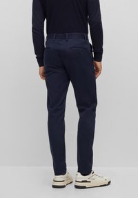 Námořnické kalhoty z hladkého materiálu, s volným střihem, zadními kapsami a kombinované s bílými teniskami s černými akcenty.