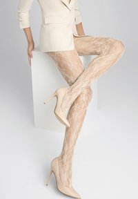 Beżowe rajstopy koronkowe z kwiatowym wzorem, teksturowany design, noszone z nude lakierowanymi szpilkami. W komplecie z jasnym żakietem.