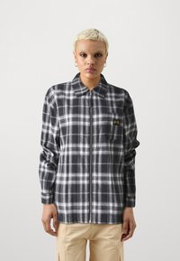 Black and white plaid shirt with zip front, collar, left chest pocket, and long sleeves; flannel texture, relaxed fit.