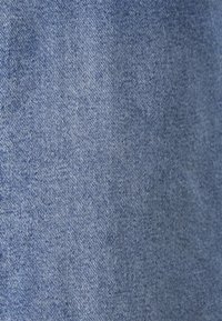 Svetle modrá džínovina s hladkou strukturou, charakterizovaná diagonálním tkaním a subtilními barevnými variacemi.