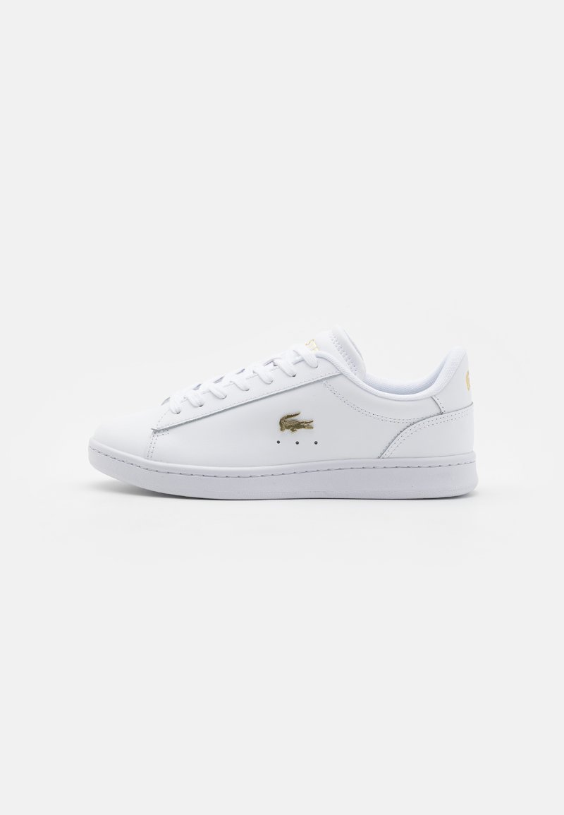 Sneaker din piele albă cu design cu șireturi, având un mic logo auriu pe lateral și perforații subtile pentru ventilație.