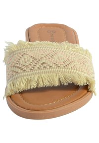 Geweven beige slide sandaal met franjes op de band, tan kleurige neplederen voetbed en lichte steun voor de voetboog. Textuur oppervlak met decoratieve patronen.