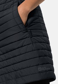 Zwarte geïsoleerde vest met een geborduurd patroon, schuine stiksels, zijzakken met ritsen en een subtiele merkl logo op de zoom.