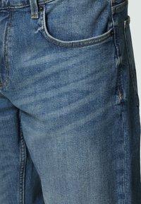 Lichtblauwe denim jeans met een klassieke pasvorm. Voorzien van zichtbare stiksels, vijf zakken en subtiele vervagingen voor textuur.