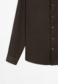 Camicia marrone scuro a maniche lunghe con polsino abbottonato e bottoni frontali, mostrata dalla metà del busto fino alla fine di una manica su sfondo bianco.