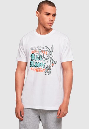 Man wearing a white t-shirt with Bugs Bunny holding a carrot and text "Bugs Bunny and Always Authentic" in colorful letters.