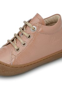 Zapato de charol rosa con un diseño redondeado, con cordones y ojales en tono dorado. Suela texturizada con un patrón sutil.