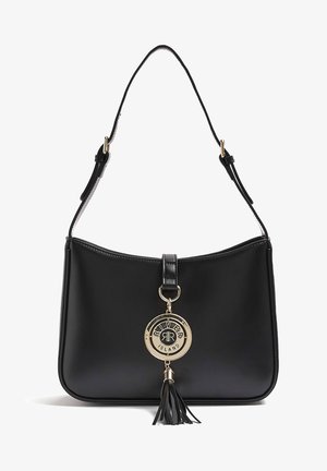 Sac à épaule en cuir noir avec bandoulière ajustable, breloque circulaire dorée avec le logo River Island, et gland en cuir noir suspendu à l'avant.
