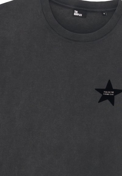 Camiseta de cuello redondo en gris oscuro con una estrella negra en el pecho que muestra el texto "TE RETO A HACERLO" y la etiqueta de la marca "THE KOOPLES" en el interior del cuello.