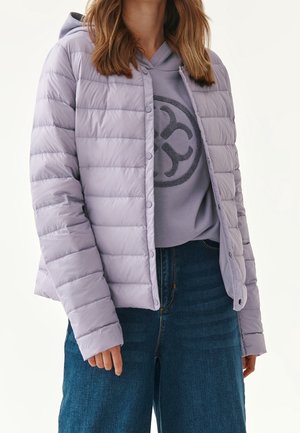 Lyse lilla, fyldige jakke med horisontale quiltede mønster og trykknapper, lagdelt over en grå hoodie med et rundet logo, parret med blå jeans.