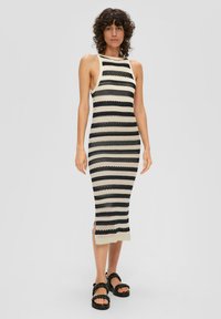 Robe midi en tricot avec une silhouette ajustée, présentant des rayures horizontales alternées en noir et crème, des fentes sur les côtés et un design sans manches.