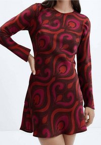 Robe à manches longues présentant un motif abstrait tourbillonnant rouge et rose sur un fond bordeaux foncé, avec un corsage ajusté et un bas évasé.