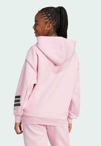 Ροζ φούτερ με κουκούλα και χαλαρή εφαρμογή, με ραμμένα μανίκια και τρεις μαύρες ρίγες στον αριστερό μανίκι. Μαλακή υφή υφάσματος.