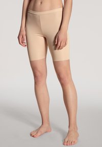 Beige stretch shorts gemaakt van zachte, lichtgewicht stof, met een brede, elastische tailleband en een knielange ontwerp.