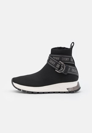 Sort ankelhøj sneaker med hvid sål, elastiske DKNY-mærkede remme, der krydser foran, og en trækketab bagpå.