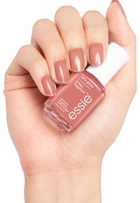 Bouteille de vernis à ongles tenue dans une main. La bouteille est rose avec un capuchon blanc, étiquetée "essie jelly gloss." Les ongles sont peints d'une teinte rose doux assortie.