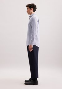 Camicia a maniche lunghe a scacchi blu chiaro con polsini bottonati, abbinata a pantaloni eleganti blu scuro e scarpe eleganti nere.