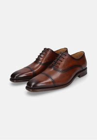 Scarpe eleganti in pelle marrone con un design raffinato, punta affusolata, dettagli brogue sulla parte superiore e lacci a cinque fori. Texture liscia e finitura lucida.
