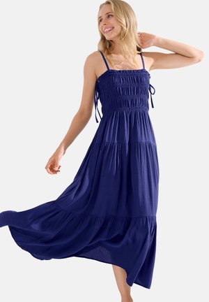 Robe maxi bleu marine en tissu léger avec un corsage froncé, de fines bretelles ajustables, et une jupe à volants qui s'écoule doucement.