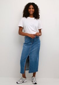 Jeans-Maxi-Rock mit einem vorderen Schlitz, blaue Farbe, hochsubtler Entwurf, aus weichem Stoff. Kombiniert mit einem schlichten weißen T-Shirt und Turnschuhen.