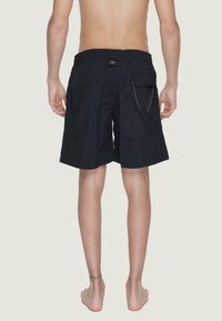 Pantaloni da bagno neri con vita elastica, tasche laterali e una tasca posteriore con chiusura a bottone e dettagli in cucitura gialla.