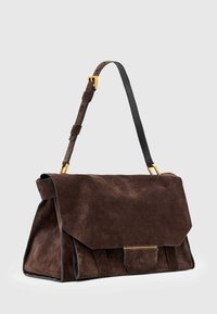 Bruine suède handtas met een omgevouwen klep, gouden hardware accenten en een afneembare leren strap. Bevat zijsplitsingen voor een ontwerpelement.