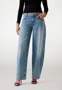 Jeans a gamba larga di colore blu chiaro realizzati in denim, con una finitura sbiadita, design a cinque tasche e chiusura con bottone.
