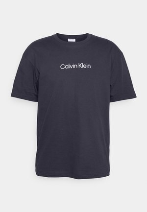 Camiseta de algodón azul marino con mangas cortas y cuello redondo, con el logo blanco de "Calvin Klein" impreso en la parte delantera.