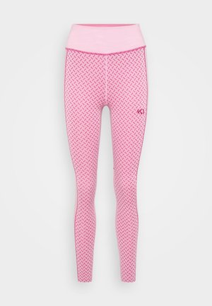 Rosa leggings med et mønster bestående av små former, høy midje og kontrasterende sømmer. Materialet virker elastisk og glatt.
