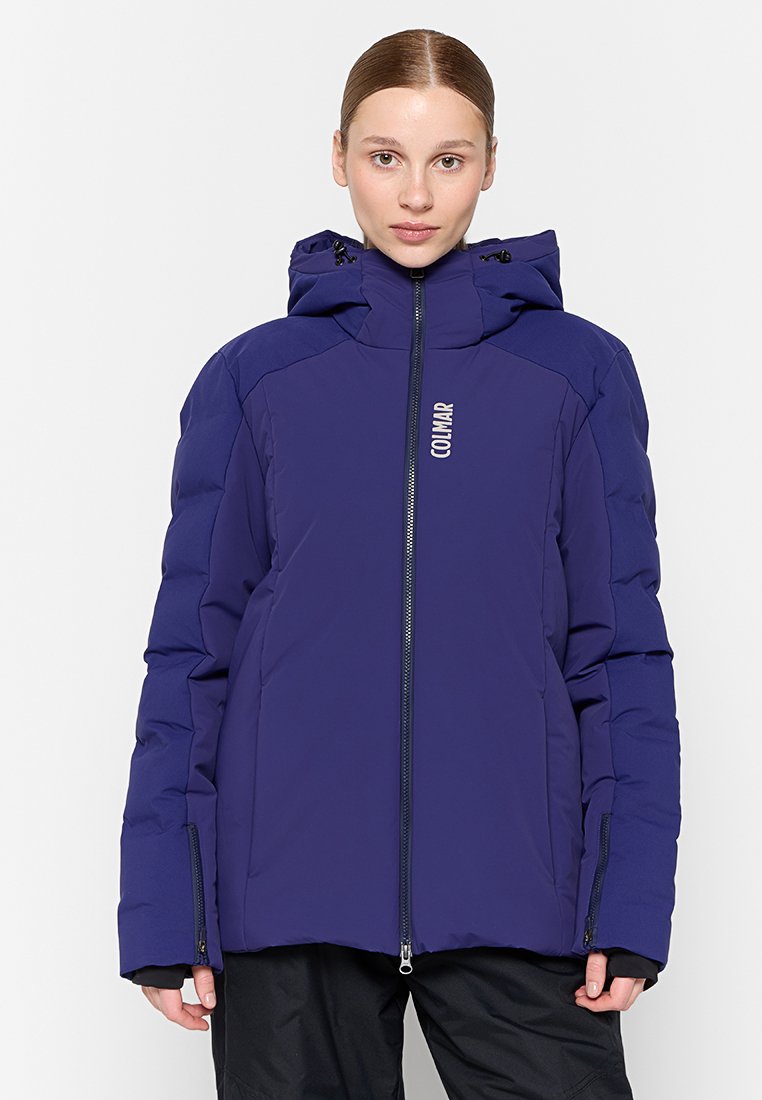 Giacca puffa viola con zip frontale, cappuccio e dettagli con logo. Presenta un design imbottito e tasche laterali. Materiale anti vento e isolante.