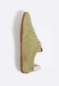 Zielone zamszowe sneakersy o teksturowanej powierzchni, gumowej podeszwie i beżowych sznurówkach. Charakteryzują się zakrzywioną formą i małą pętelką na pięcie.