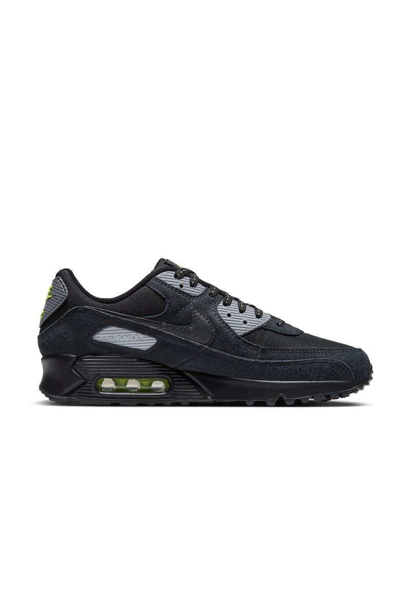 Zapatilla negra con una mezcla de materiales de ante y malla. Presenta una unidad Air Max visible, detalles en gris y amortiguación de aire verde.