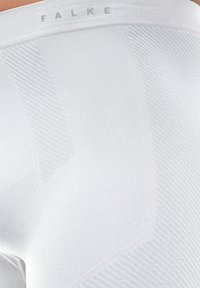 Collants blancs à la texture lisse, arborant de subtils lignes diagonales et le mot "FALKE" imprimé en gris clair sur la taille.